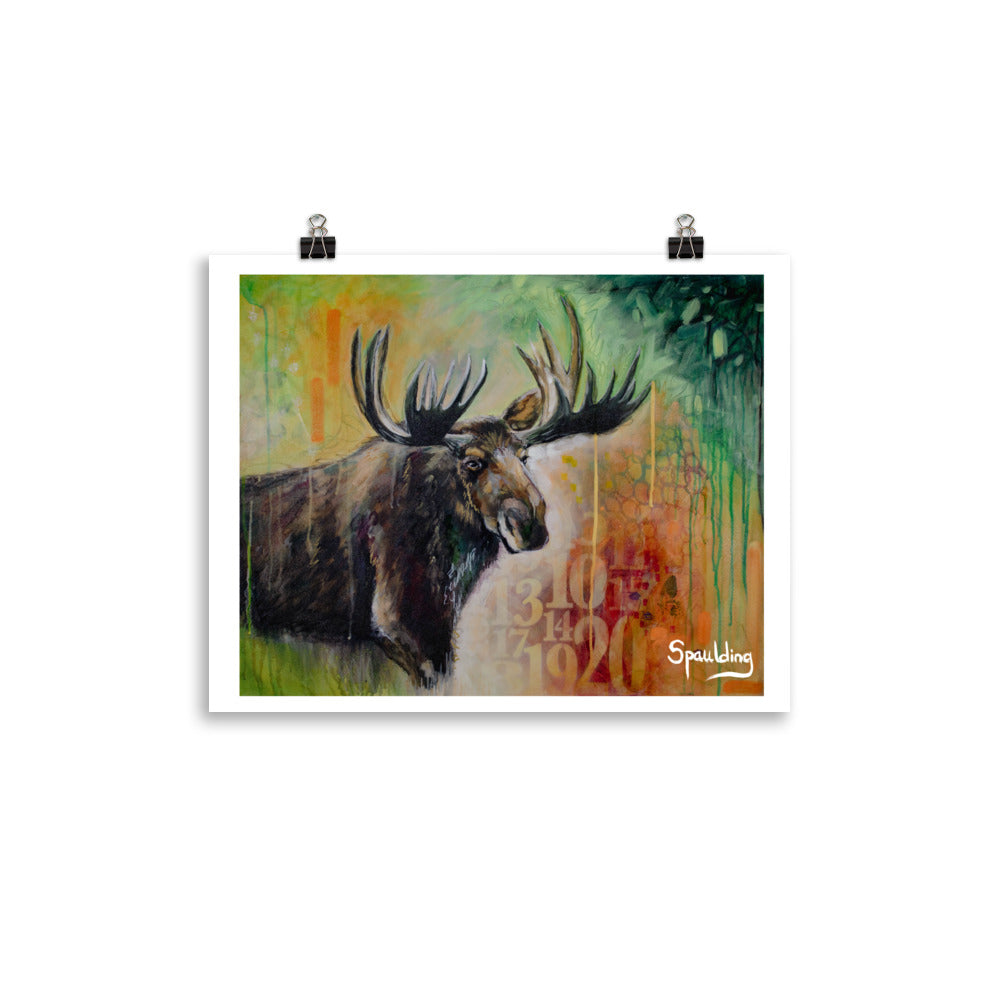 Paper art print of a bull moose with antlers in front of a background of yellows,oranges, reds and green.