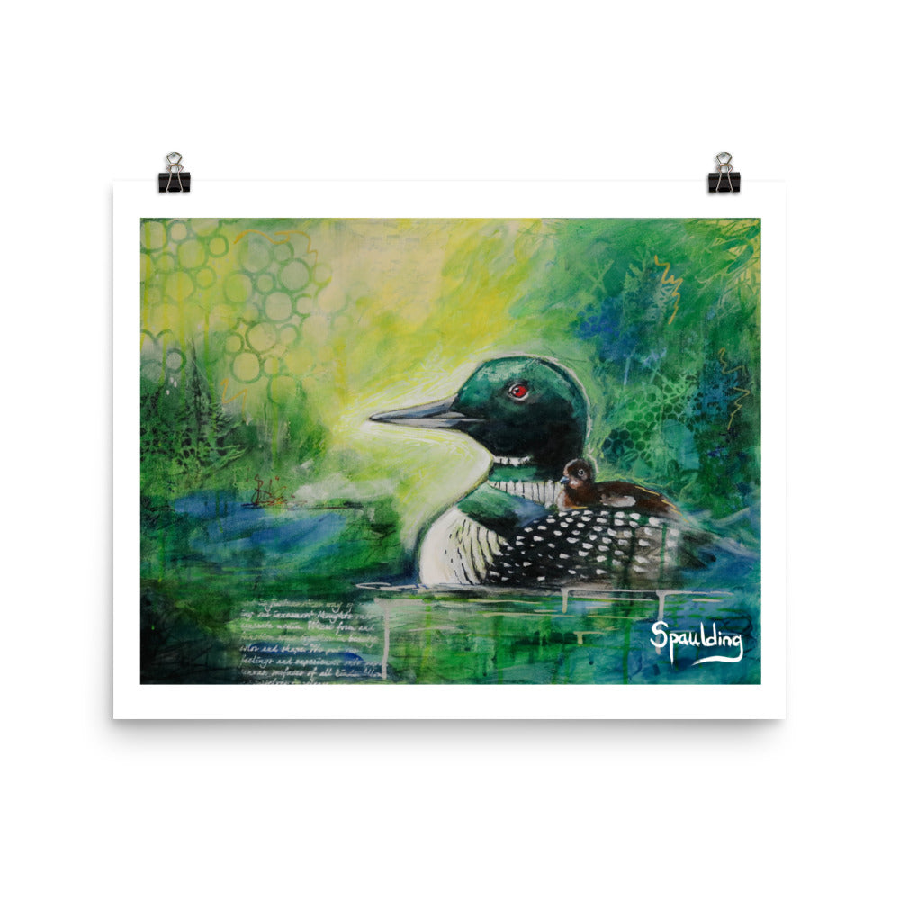 Paper art print of a black and white loon with a brown fuzzy baby on it's back. The background is a color scheme of yellows, greens and blues.