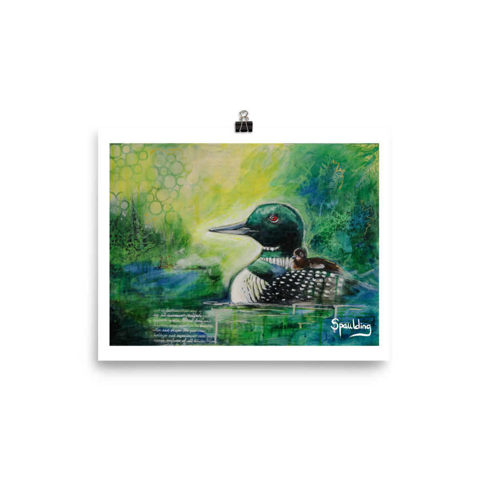 Paper art print of a black and white loon with a brown fuzzy baby on it's back. The background is a color scheme of yellows, greens and blues.