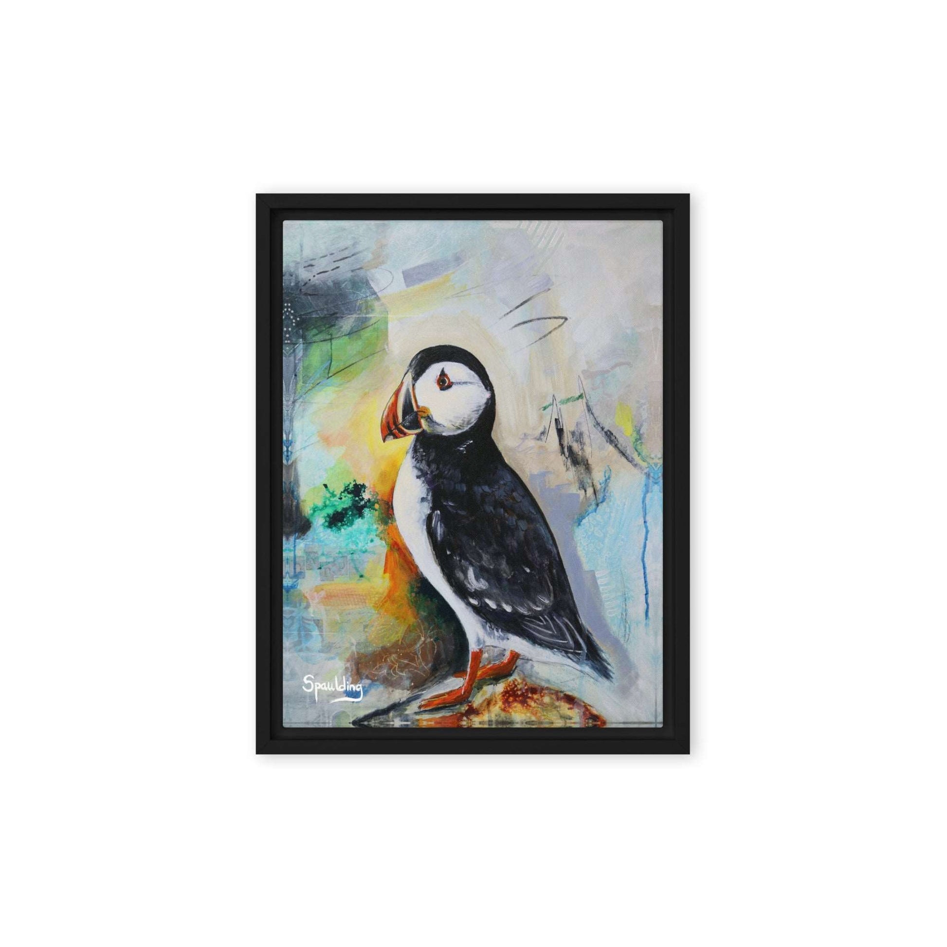 Framed canvas print of a black and white puffin with orange beak and feet standing on a rock. The background is a color palette of light tans, yellows, blues, greens and some black. 
