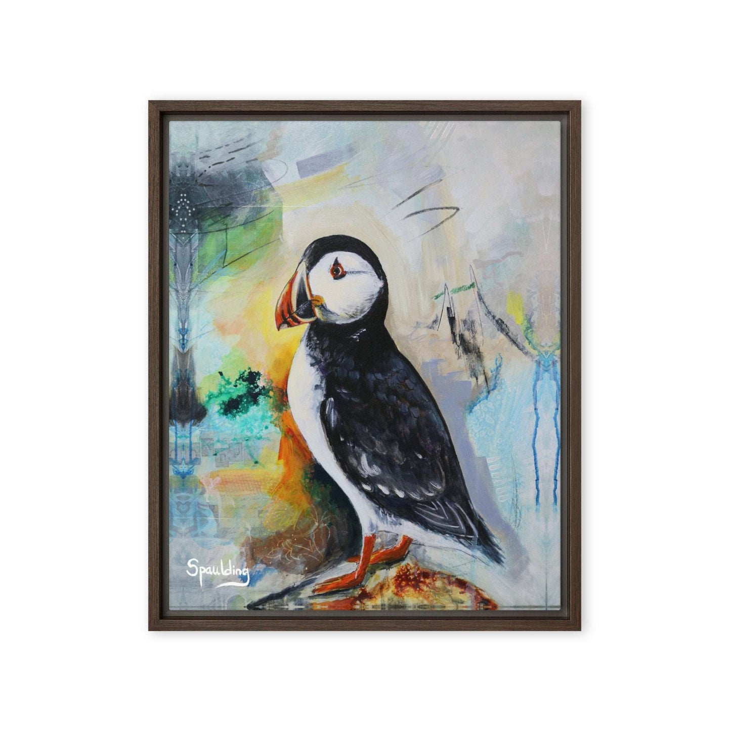 Framed canvas print of a black and white puffin with orange beak and feet standing on a rock. The background is a color palette of light tans, yellows, blues, greens and some black.
