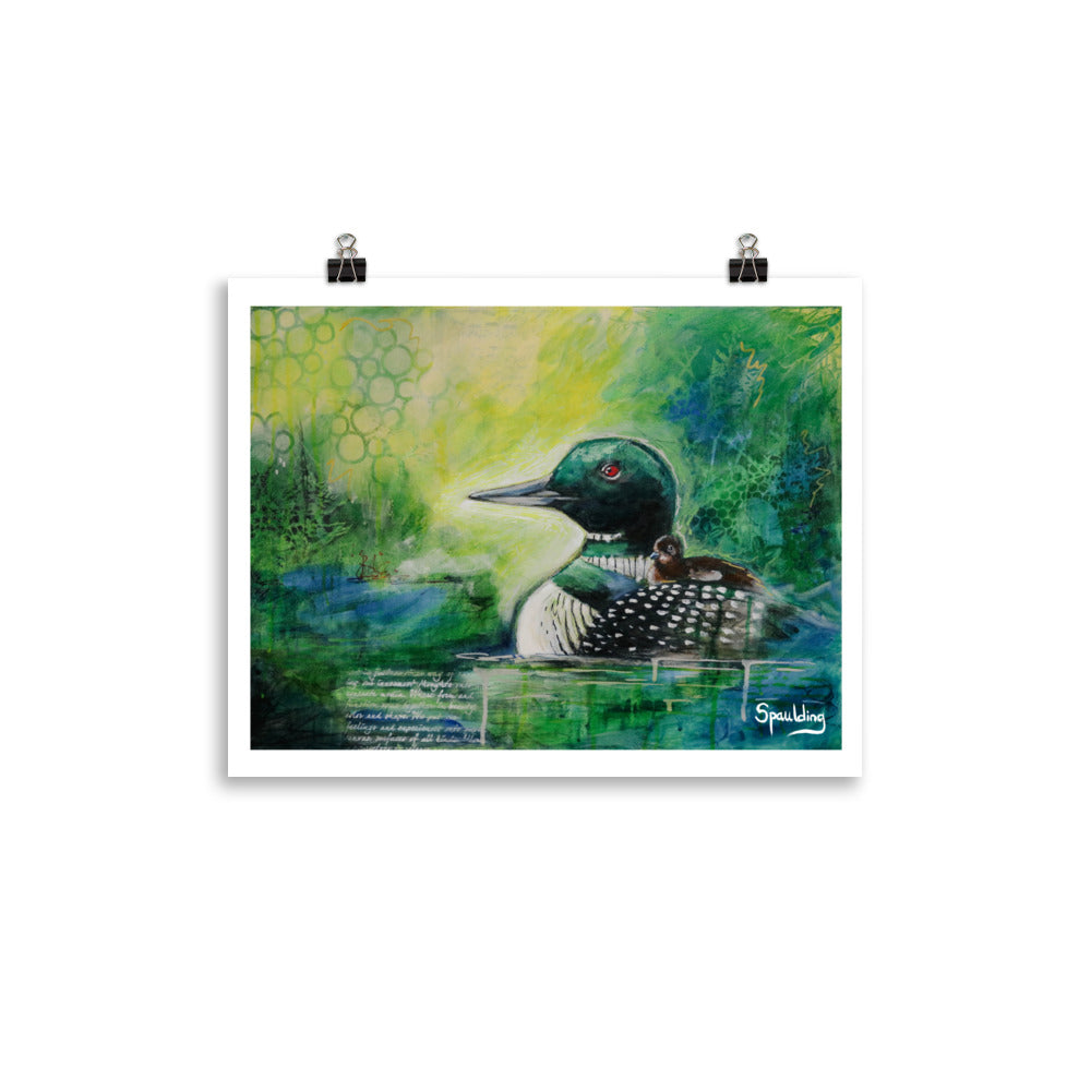 Paper art print of a black and white loon with a brown fuzzy baby on it's back. The background is a color scheme of yellows, greens and blues.