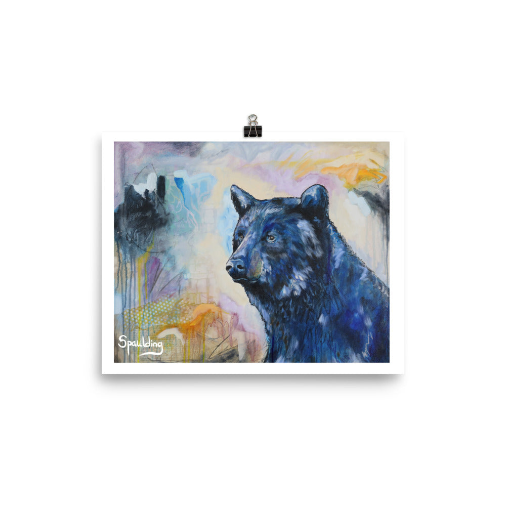 Paper art print of a black bear with a background of tan, orange, blues and black.